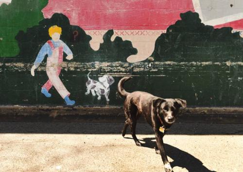 section of mural depicting boy and his dog with real do standing in front
