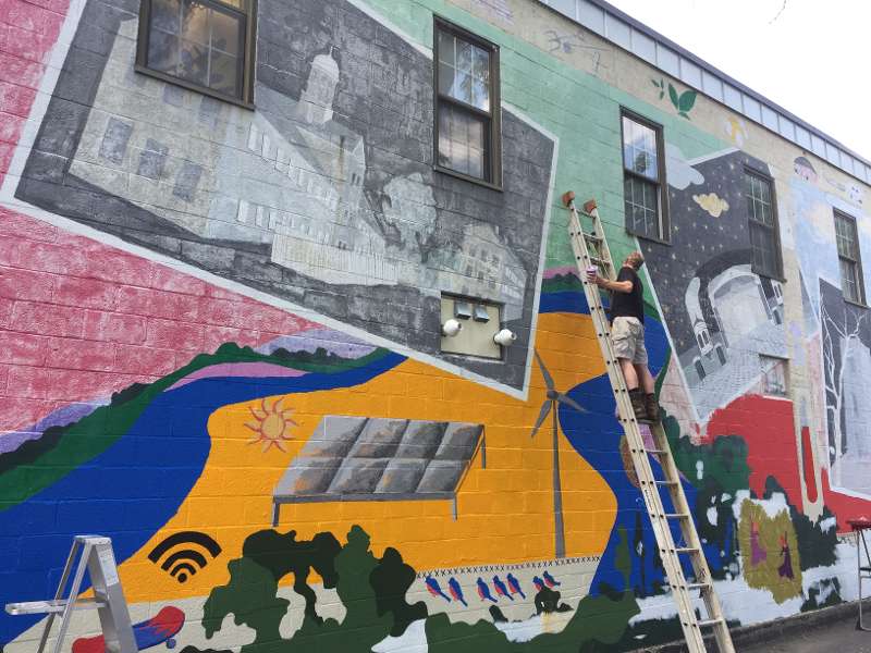 Someone on a ladder working on the mural